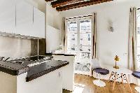 functional kitchenette and dining area with a table and two modern chairs in a studio Paris luxury a