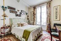 charming bedroom with a double size bed with the finest linens and a desk in a 1-bedroom Paris luxur