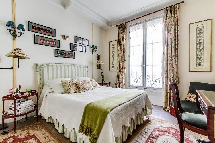 charming bedroom with a double size bed with the finest linens and a desk in a 1-bedroom Paris luxur