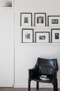 black stylish chair beneath framed blac-and-white photographs in Paris luxury apartment