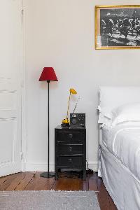 comfy bed with red floor lamp in Paris luxury apartment
