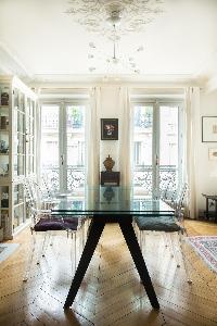 elegant dining area with glass-topped table surrounded by ghost chairs in Paris luxury apartment