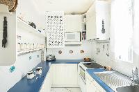 neat kitchen with royal blue and white hues in Paris luxury apartment