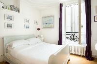 pretty second bedroom with an array of still life artworks above the double bed in Paris luxury apar
