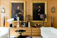 elegant sitting room with a pair of large portraits in gilded frames hang above contemporary furnitu
