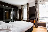 master bedroom tiled in sleek black with coffee-colored drape windows in Paris luxury apartment