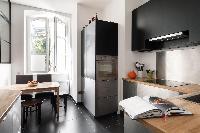 smart kitchen with a striking interior window, and wooden table for 4 in a 4-bedroom Paris luxury ap