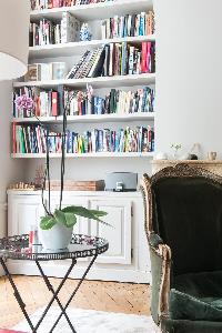 elegant moss green armchair and piles of books behind in Paris luxury apartment