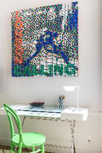 glass study with green chair beneath framed puzzle artwork in Paris luxury apartment