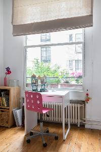 white study and pretty pink chair facing the window framed the verdant courtyard in Paris luxury apa