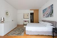 second bedroom with white-painted walls, wood floors, a double bed and a taupe single bed in Paris l