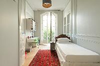 third bedroom with single bed, some interesting toys, study desk, and French window in a Paris luxur