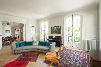 long grey sofa with colorful carpet rug and old piano overlooking the courtyard  in a Paris luxury a