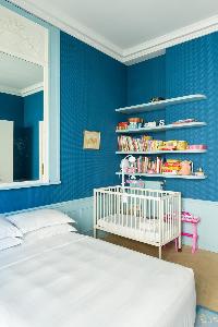a nursery room in blue hue with a baby cots and double bed in a Paris luxury apartment