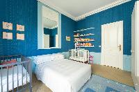a nursery room in blue hue with a baby cots and double bed in a Paris luxury apartment