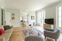 sitting room with a beige sofa and grey-colored seats with a rainbow-colored carpet lied on the parq