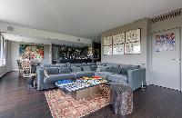 cozy living area with a collection of films and artworks, L-shaped grey sofa in a Paris luxury apart
