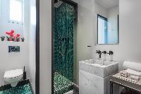 sleek bathroom with a shower, a basin, and a toilet in a 2-bedroom Paris luxury apartment