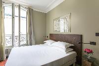 cozy bedroom with double bed and taupe walls in a 2-bedroom Paris luxury apartment