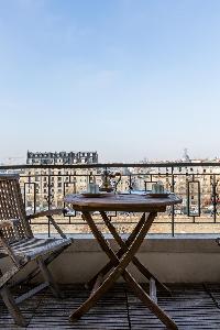wooden coffee table and chairs in balcony with view of Paris