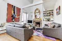 elegant living area with two grey sofas, a center table, a fireplace, and a television in a 1-bedroo