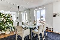 elegant dining area with a large glass table and six seats, potted plants and mirrored walls in a 1-