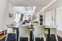 elegant dining area with a large glass table and six seats in a 1-bedroom Paris luxury apartment