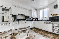fully equipped white kitchen and mini dining area in a 1-bedroom Paris luxury apartment