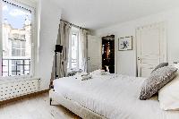 lovely bedroom with a queen-size bed, built-in closet, a desk and a pullout bed in a Paris luxury ap