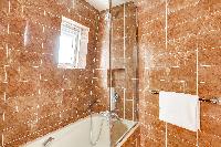 elegant brown-tiled en suite bathroom with a toilet, a sink with mirror, and full bath with shower i