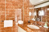 elegant brown-tiled en suite bathroom with a toilet, a sink with mirror, and full bath with shower i