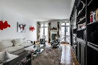 well-lit and spacious living area with two white sofas, black built-in bookshelf filled with books, 