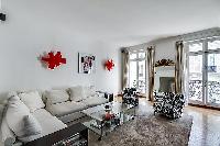 well-lit and spacious living area with two white sofas, big mirror,  grey carpet rug, and tall Frenc