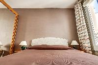 bedroom with a large wooden wardrobe closet with a full-length mirror placed beside the bed in paris