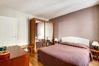 bedroom with a large wooden wardrobe closet with a full-length mirror placed beside the bed in paris