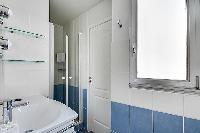 blue-tiled bathroom furnished with a shower area, a sink, a mirror, and a hairdryer in paris luxury 