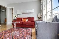 living area with red sofa bed and ghost round center table in paris luxury apartment