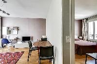 living area with a desk, a television and a three-seater dining area with access to the bedroom in p
