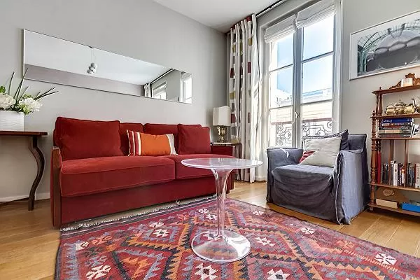 living area with red sofa bed and ghost round center table in paris luxury apartment