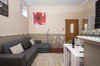 open-plan living area with a gray sofa bed, gray and white cushions, a TV, stylish lamps, white dini