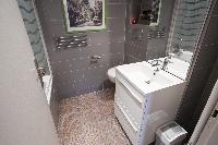 modern bathroom with gray tiles, a bathtub with integrated shower, and a toilet in a Paris luxury ap