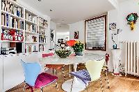 colorfully designed dining area for 4 with bookshelves in a Paris luxury apartment