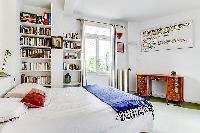 first bedroom with queen size bed and book shelves in a Paris luxury apartment