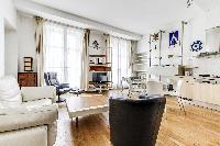 spacious living area with double-glazed windows, sofa, armchairs, paintings, shelves, nightstand, an