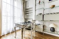 working space with a desk and chair in front of a bright tall window in a 2-bedroom Paris luxury apa