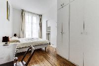 second bedroom with 2 single beds, closets, desk and chair in a 2-bedroom Paris luxury apartment