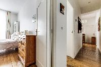 first bedroom and hallway with rustic interiors in a 2-bedroom Paris luxury apartment