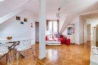 spacious living area with wooden floor, white walls, red sofa, and stylish dining area