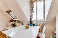 dining area with white dining table, stylish white chairs overlooking Paris