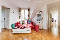 white-walled living area with red sofa and turquiose furniture in a 2-bedroom Paris apartment